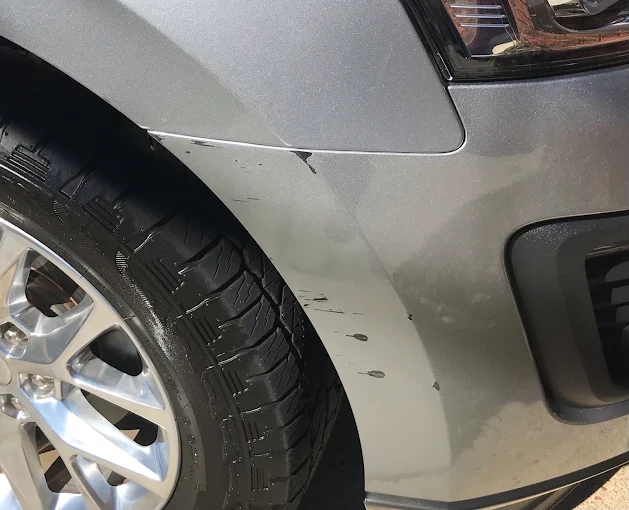 Scratched silver vehicle front fender before repair